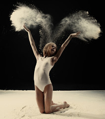 Little cute girl dancing with white powder on black background