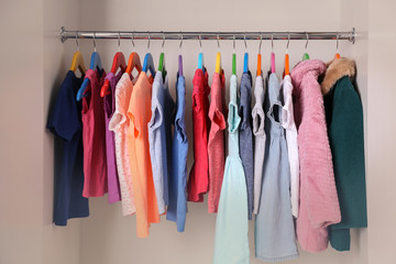 Colourful clothes on hangers in wardrobe