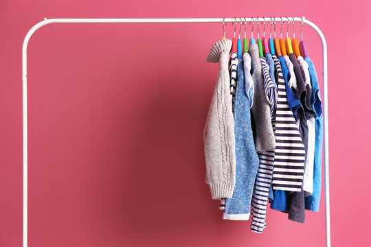 Hangers with colourful clothes on pink background