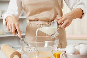 Woman making dough for a pie in a glass bowl