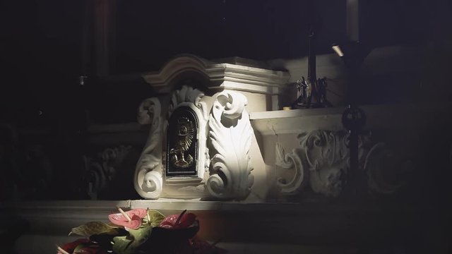 The stone altar of a dark church, with flowers and mystic symbols, a ray coming from outside. Religious, sacred symbolic shot. Mojo tones. Aurora lights appear as an overlay.

