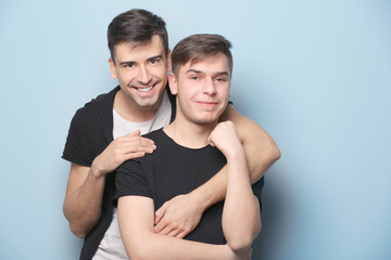 Fototapeta na wymiar Happy gay couple posing on light background