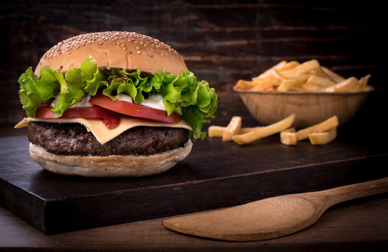 beef burger with salad and tomato on top of a wooden board and rustic background