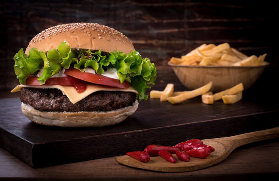 Traditional spicy beef burger with salad and tomato on top of a wooden board and white background