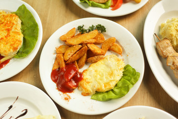 chicken in cheese with a side dish and lots of tasty dishes on the table in the restaurant