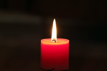 Burning candle on a dark blured background