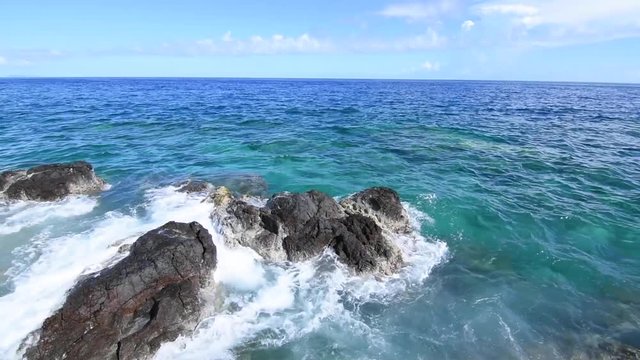 Waves washing over rocky reef shoreline with deep clear water at Punta Soldado in Isla Culebra, with native sound