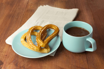 Spanish churros, chocolate, blurred newspaper, and copyspace