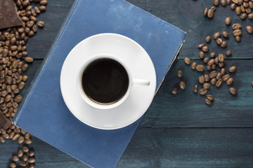 Coffee cup with old books, chocolate piece and grains
