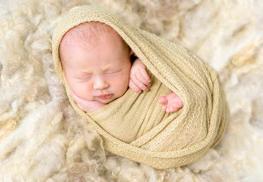 Infant enveloped tightly, resting, closeup