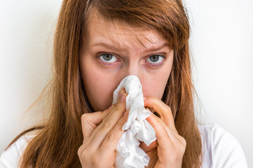 Woman with allergy or flu cold symptoms sneezing in tissue