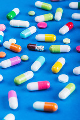 different color tablets and pills on a blue background