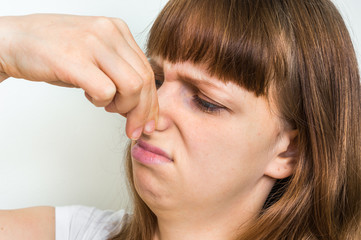 Woman holding her nose - bad smell concept