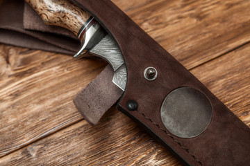 Hunting damascus steel knife handmade on a wooden background, close-up © hdesert