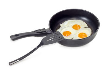 Three fried eggs in the frying pan and spatula