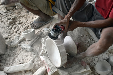 worker carving limestone using handheld machine