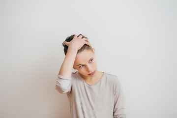 Portrait of a teenager boy touching his hair on a light background