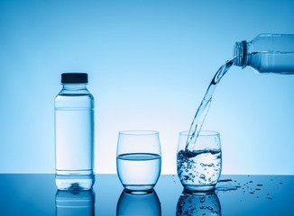 Bottle with creative splashing water in the glass