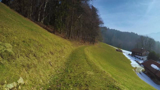 Point of view shot of walking on a hill towards a forest alongside a farmhouse in bavaria, germany