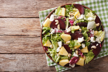 Healthy food: salad of beets, pineapple, goat cheese and greens mix closeup. horizontal top view