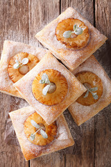 Puff pastry cake with pineapple, decorated with mint and powdered sugar close-up. vertical top view