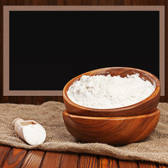Flour in wooden bowl with place for text. Closeup.