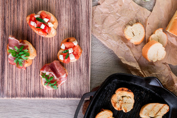 toast on grill pan. Set of crostini with tomato, arugula, prosciutto and mozzarella. Italian food, homemade bruschetta.
