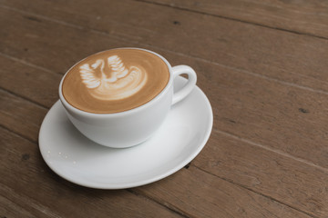 White cup of coffee on wooden table in the coffee shop.