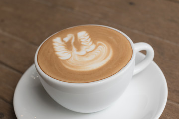 White cup of coffee on wooden table in the coffee shop.
