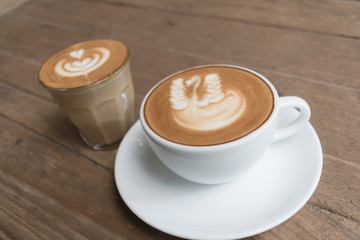 White cup of coffee on wooden table in the coffee shop.