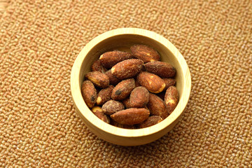Salt roasted almond in wooden bowl. on brown Napery.