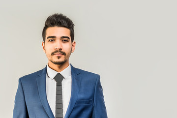 Young attractive man in a blue suit on a gray background. Isolated