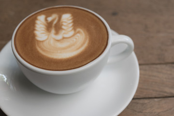 White cup of coffee on wooden table in the coffee shop.