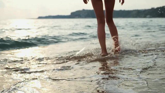 Young woman in white bikini walking on a beach