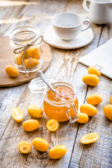 kumquat on plate and jam in jar at wooden table