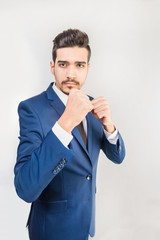 Young attractive man in a blue suit standing in a fighting stance on a gray background. Isolated