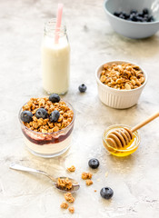 Morning granola in glass with yogurt, honey and milk on white desk