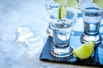 Silver tequila shots with lime and salt on gray stone background