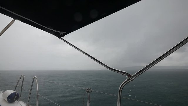 Yacht movement during rain on background of sea waves in Greece. Regatta. Adventures in the ocean. Slow motion.
