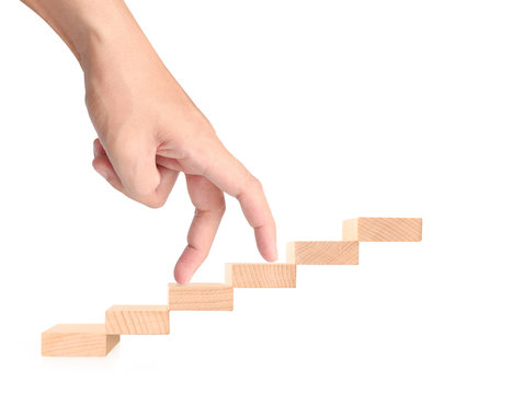 Hand liken business person stepping up  toy staircase