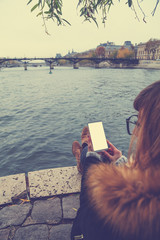 Girl using phone on pont neuf in Paris, near Seine river.