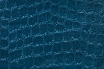 Blue background from a soft upholstery textile material, closeup. Fabric with pattern imitating crocodile skin.. Textured backdrop.