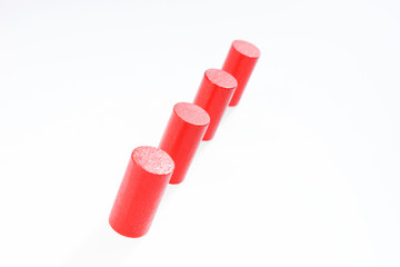 Four red round wooden building blocks in a row one behind the other