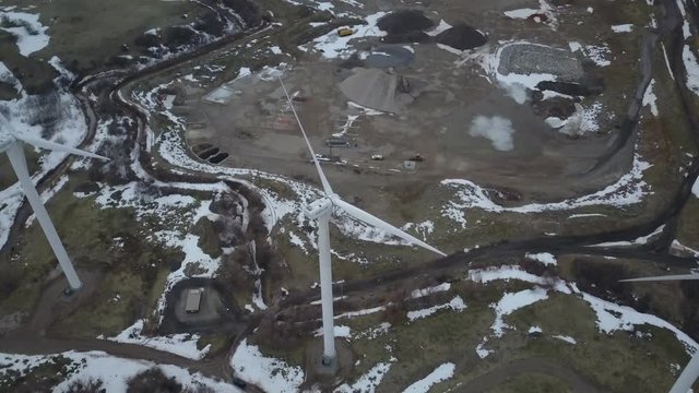 Aerial windmill turbine from above winter snow. Wind farm source of renewable energy. Computer controlled motors. Towers nearly 280 feet tall. Wind power energy for homes and business.