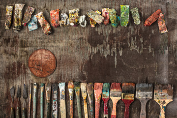 paint brushes and tubes of oil paints on wooden background