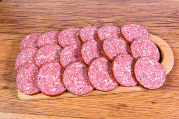 Close-up of chopped smoked sausage on a wooden board.