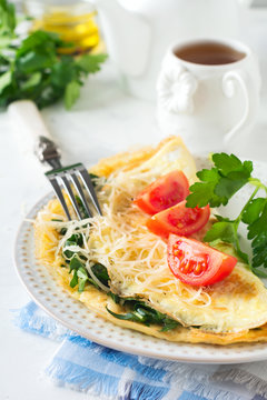 Omelet with spinach, parsley and cheese for breakfast on a light background. Selective focus.