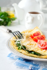 Omelet with spinach, parsley and cheese for breakfast on a light background. Selective focus.
