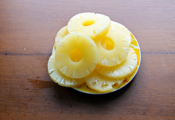 Canned pineapple on a plate on wooden table