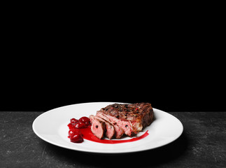 Sliced tasty steak with spices and sauce on white plate